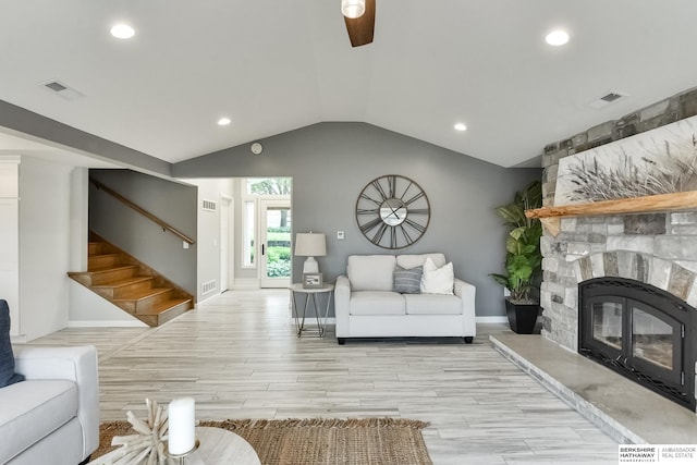 living room with lofted ceiling, a stone fireplace, and light hardwood / wood-style floors