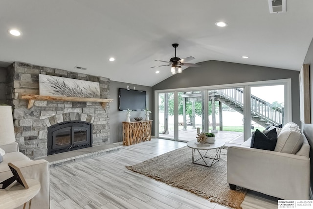 living room featuring light hardwood / wood-style floors, lofted ceiling, a fireplace, and ceiling fan