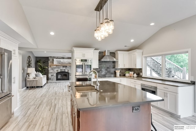 kitchen featuring appliances with stainless steel finishes, lofted ceiling, white cabinetry, and a center island with sink