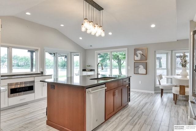 kitchen with lofted ceiling, sink, appliances with stainless steel finishes, and an island with sink