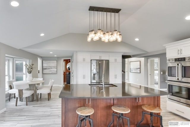 kitchen featuring a spacious island, white cabinetry, a kitchen bar, vaulted ceiling, and stainless steel appliances