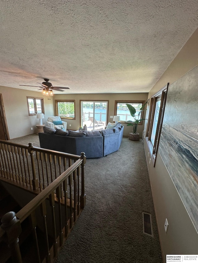 carpeted living room with a textured ceiling and ceiling fan