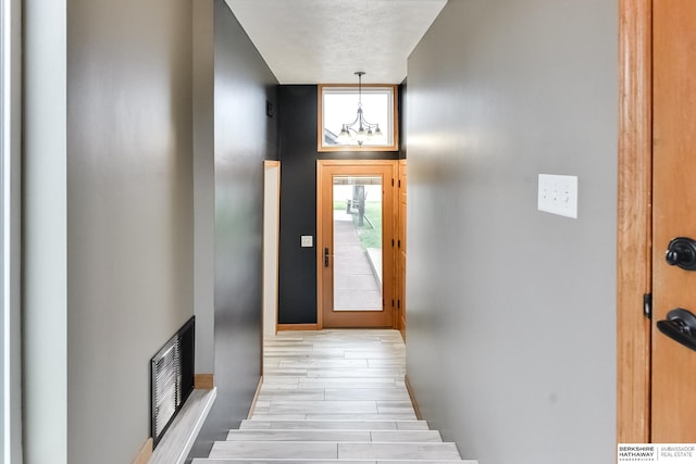 interior space with a textured ceiling, a chandelier, and light wood-type flooring