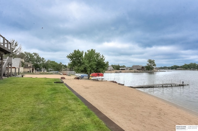 view of dock with a lawn and a water view