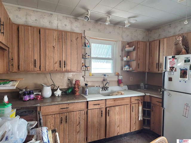 kitchen featuring open shelves, brown cabinetry, a sink, and freestanding refrigerator