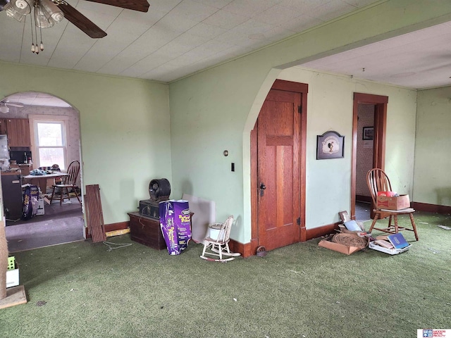 interior space featuring a ceiling fan, arched walkways, and carpet flooring