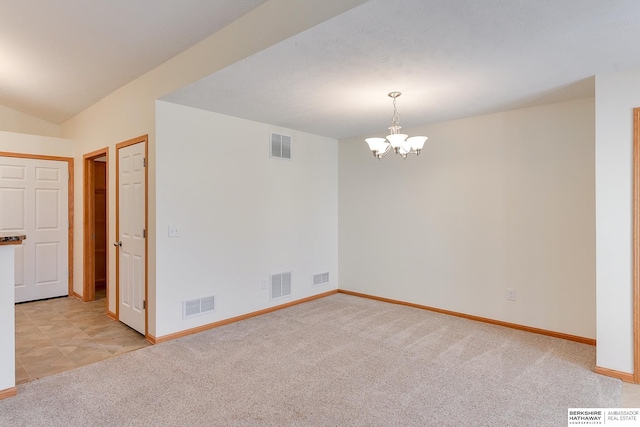 carpeted empty room with vaulted ceiling and an inviting chandelier