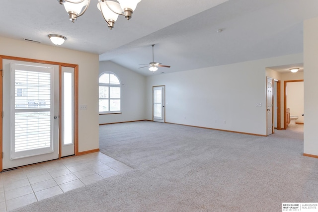 carpeted foyer entrance with a wealth of natural light, ceiling fan with notable chandelier, and vaulted ceiling