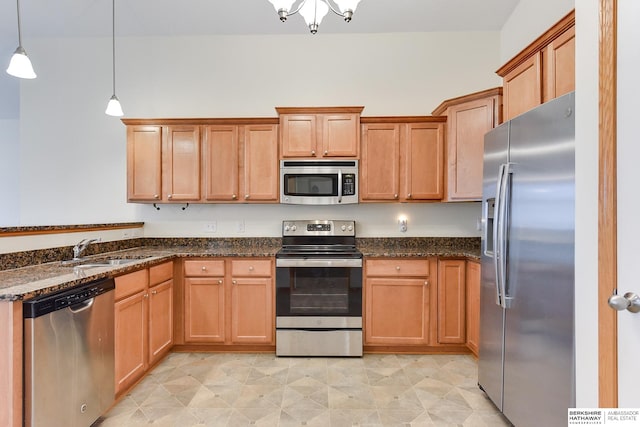 kitchen featuring dark stone countertops, pendant lighting, appliances with stainless steel finishes, and sink