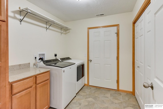 washroom featuring cabinets, washer and clothes dryer, and a textured ceiling