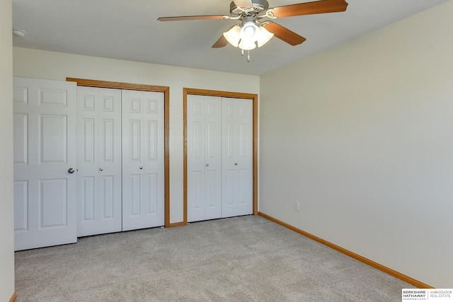 unfurnished bedroom featuring ceiling fan, light carpet, and multiple closets