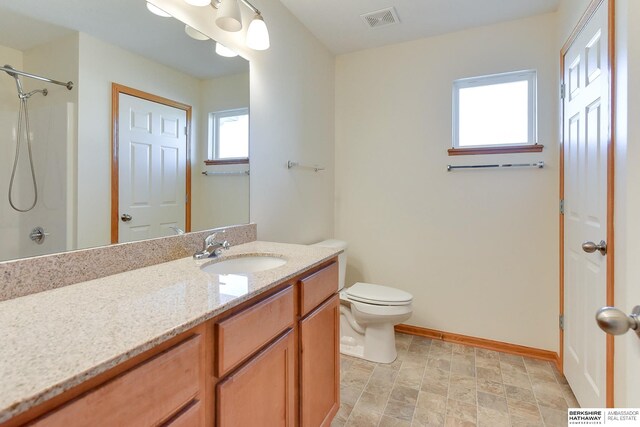 bathroom featuring a shower, vanity, and toilet