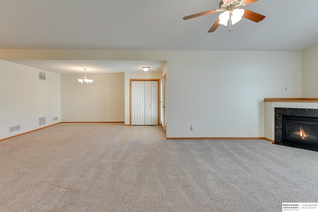 unfurnished living room featuring ceiling fan with notable chandelier and light carpet