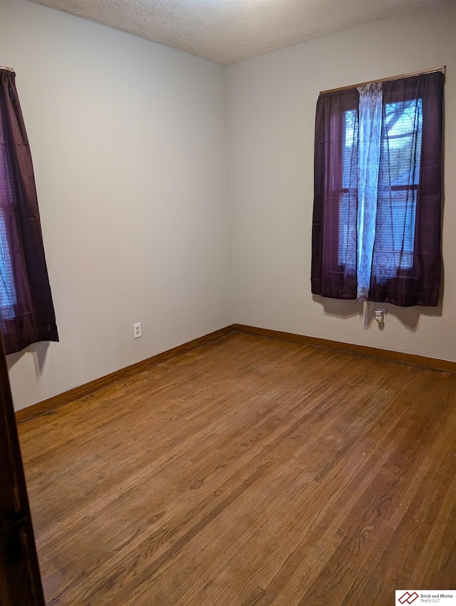 unfurnished room with a textured ceiling and hardwood / wood-style floors