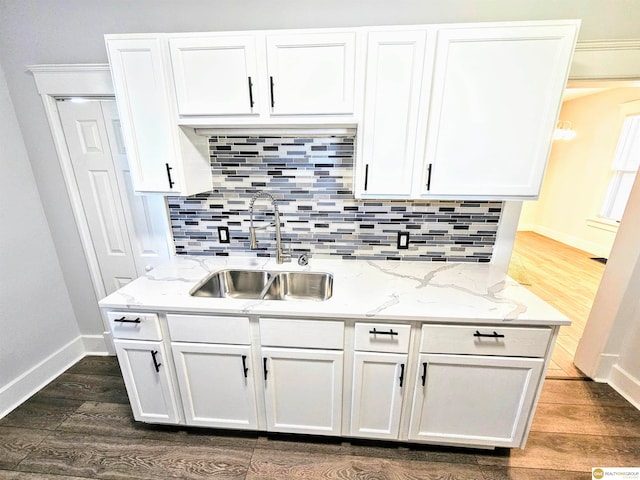 kitchen with white cabinets, dark hardwood / wood-style flooring, light stone counters, and sink