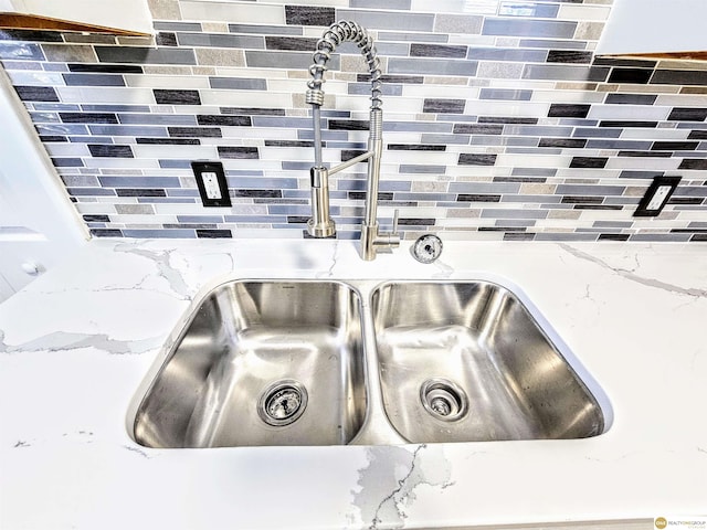 room details with backsplash, light stone countertops, and sink