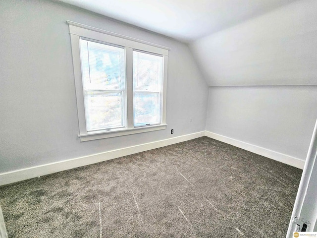 bonus room with dark carpet and lofted ceiling