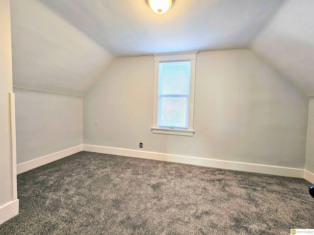 additional living space with dark carpet and lofted ceiling