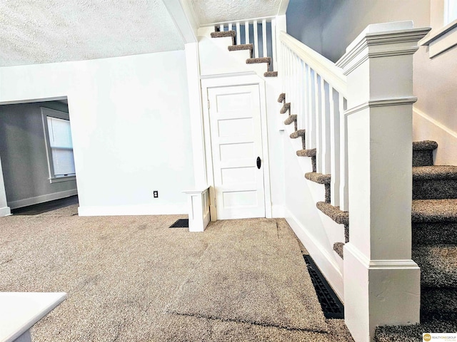 stairs featuring carpet and a textured ceiling