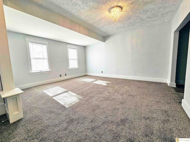 unfurnished room featuring a textured ceiling and dark colored carpet