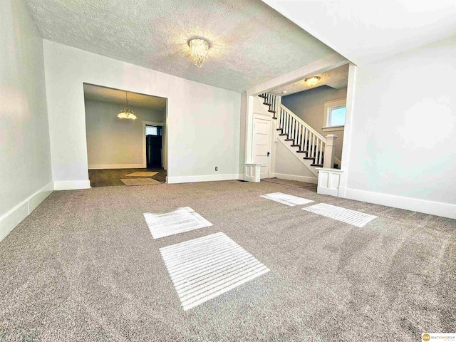 unfurnished room with carpet, a textured ceiling, and a notable chandelier