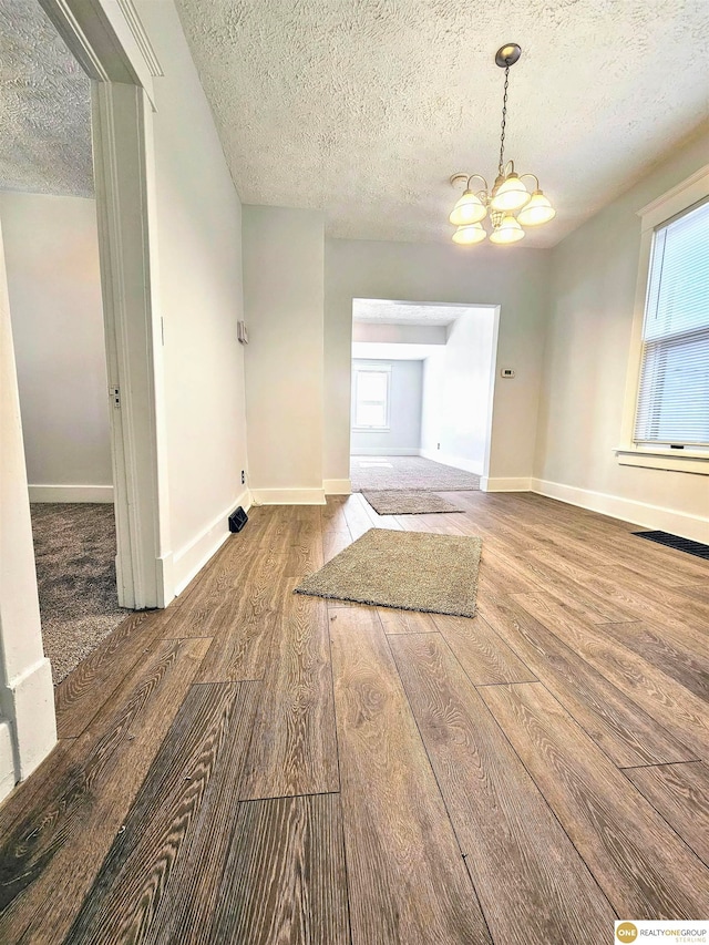 interior space with hardwood / wood-style flooring, a textured ceiling, and a chandelier