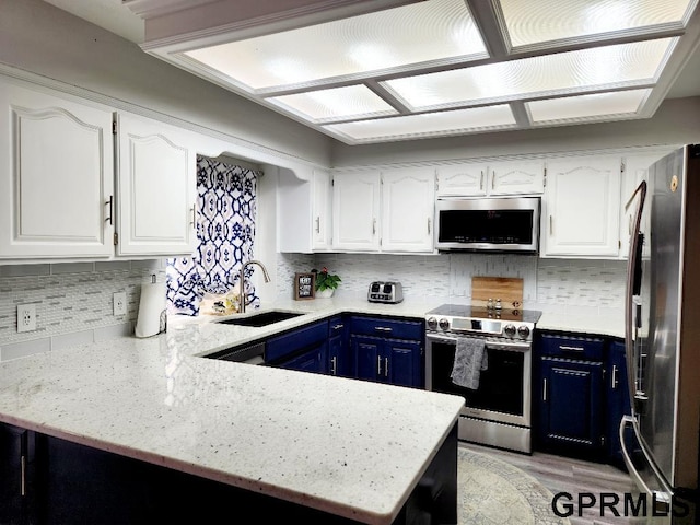 kitchen with appliances with stainless steel finishes, kitchen peninsula, blue cabinetry, and sink