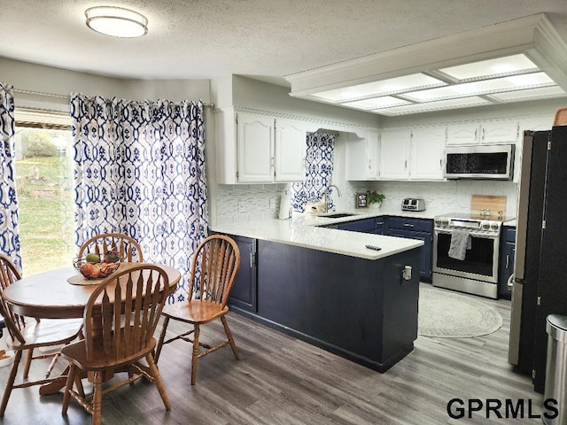 kitchen featuring kitchen peninsula, white cabinetry, stainless steel appliances, and wood-type flooring