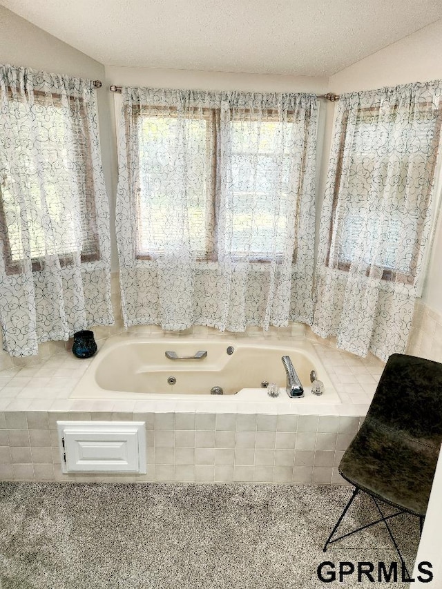 bathroom with tiled bath, a textured ceiling, and lofted ceiling