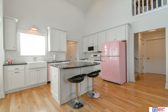 kitchen with sink, a center island, light wood-type flooring, white cabinetry, and white appliances