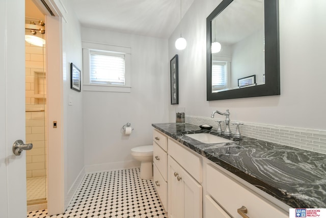 bathroom with vanity, tasteful backsplash, toilet, and a shower