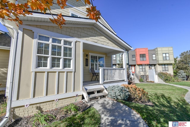 property entrance with covered porch and a lawn