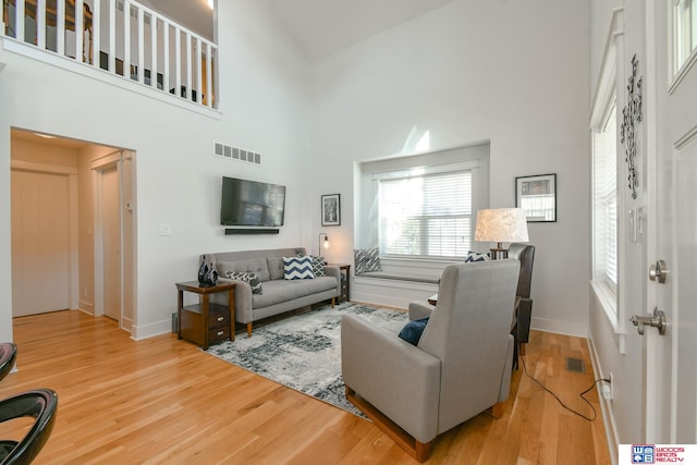 living room with light hardwood / wood-style floors and a high ceiling