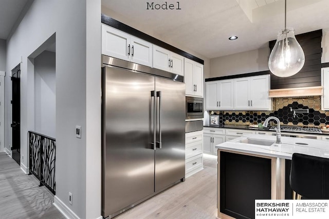 3902 S 212th St, Omaha, NE 68022 - kitchen featuring built in appliances, light wood-style floors, tasteful backsplash, a sink, and hanging light fixtures