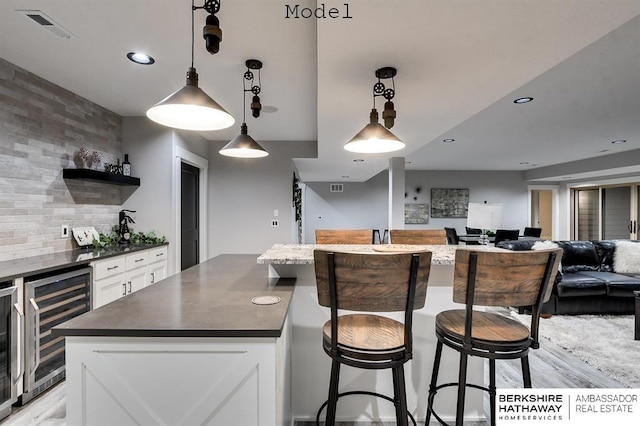 3902 S 212th St, Omaha, NE 68022 - kitchen featuring beverage cooler, dark countertops, a kitchen island, open floor plan, and white cabinets