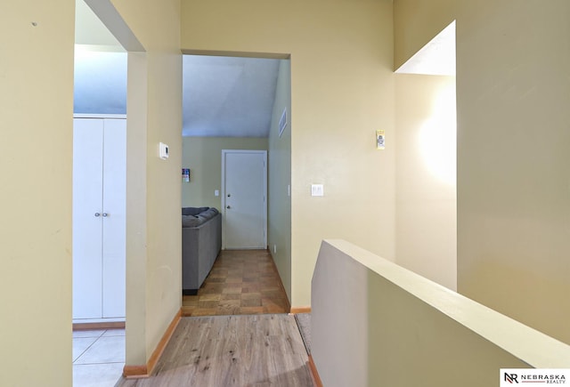 corridor featuring vaulted ceiling and wood-type flooring