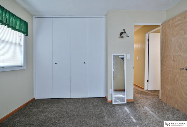 unfurnished bedroom with a closet and dark colored carpet