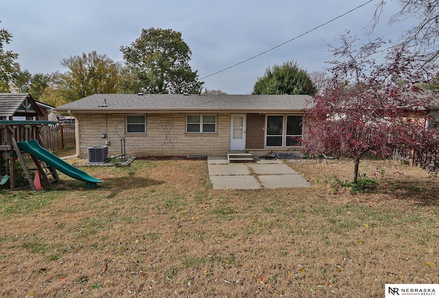 rear view of house featuring a playground, a yard, and central AC unit