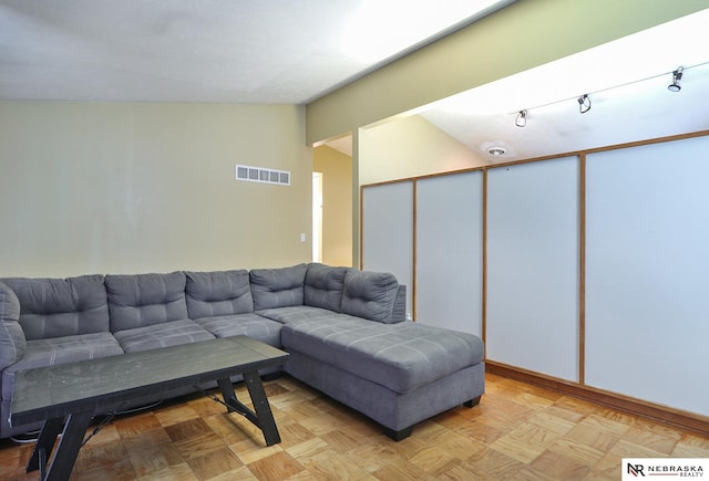 living room with lofted ceiling, rail lighting, and light parquet flooring