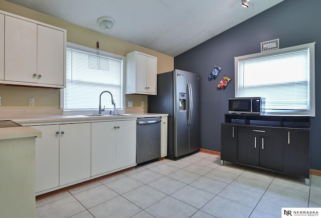 kitchen featuring lofted ceiling, white cabinets, stainless steel appliances, and light tile patterned floors