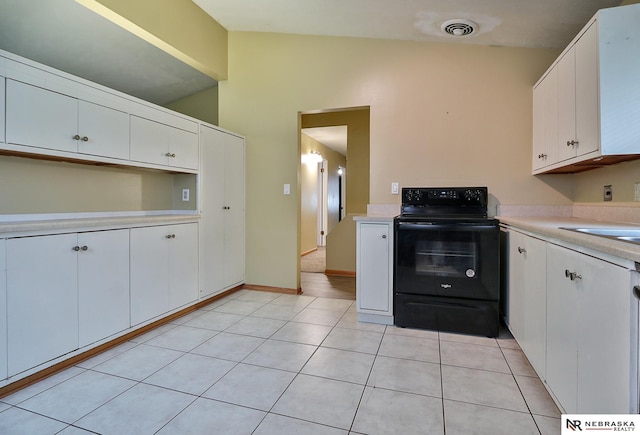 kitchen with lofted ceiling, electric range, white cabinetry, and light tile patterned floors