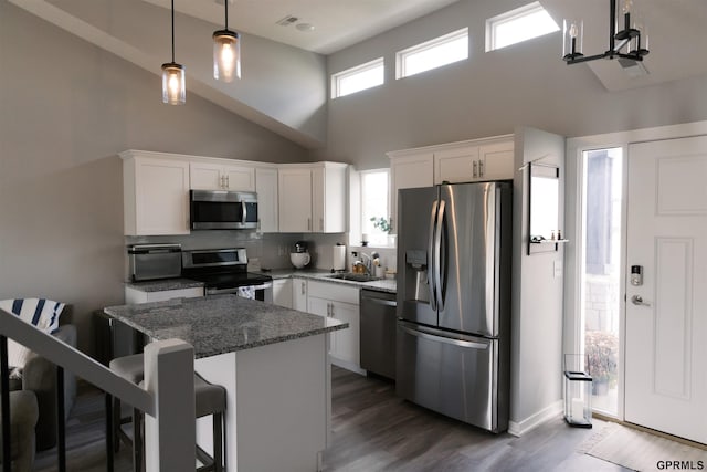 kitchen with a healthy amount of sunlight, stainless steel appliances, dark stone counters, and a kitchen bar