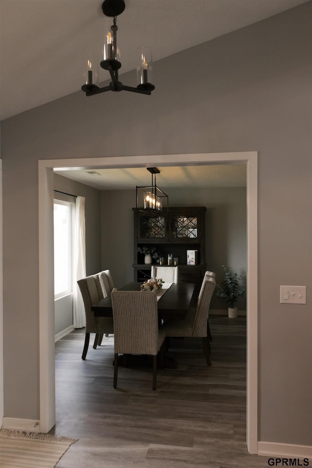 dining area featuring hardwood / wood-style flooring, a chandelier, and vaulted ceiling