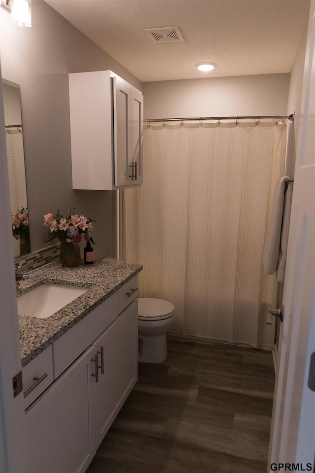 bathroom with vanity, hardwood / wood-style floors, toilet, and walk in shower