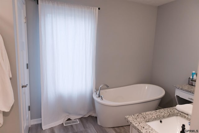 bathroom with vanity, hardwood / wood-style floors, and a tub to relax in