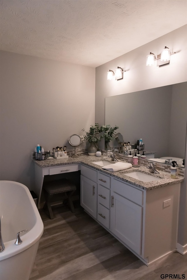 bathroom with a bathtub, a textured ceiling, hardwood / wood-style floors, and vanity