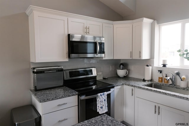 kitchen with backsplash, white cabinetry, vaulted ceiling, sink, and stainless steel appliances