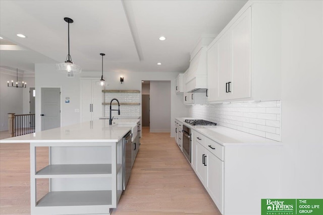 kitchen with white cabinetry, a large island with sink, and light hardwood / wood-style flooring