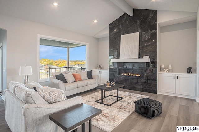 living room featuring a premium fireplace, hardwood / wood-style flooring, and vaulted ceiling with beams