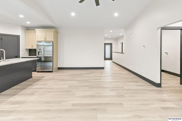 kitchen featuring ceiling fan, stainless steel fridge with ice dispenser, light wood-type flooring, and light stone counters